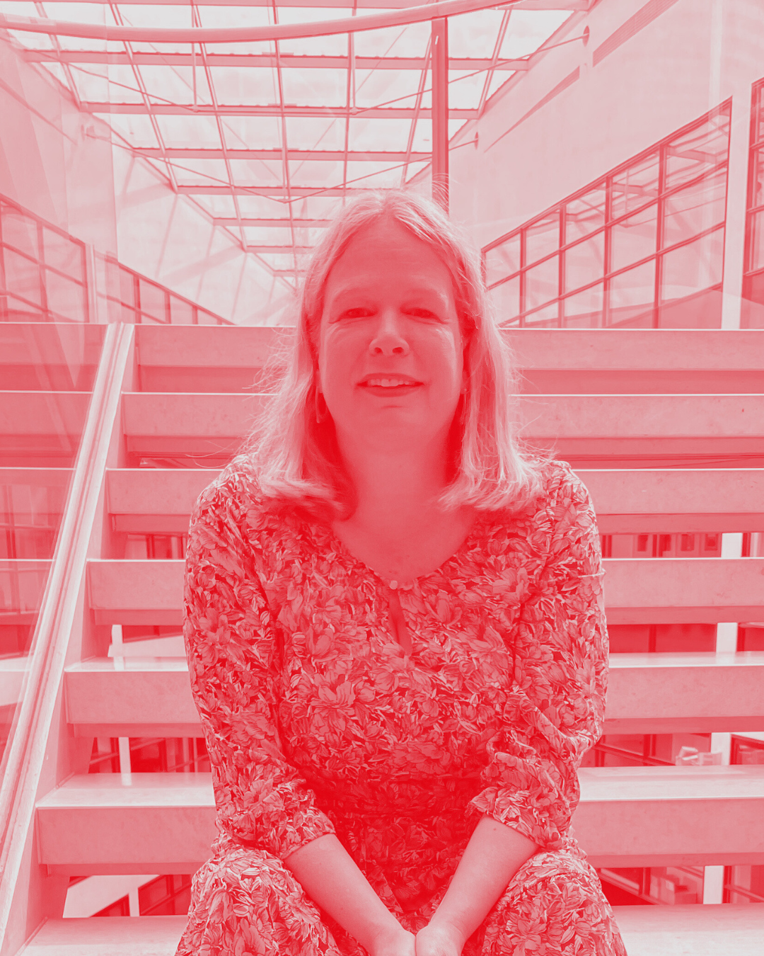 Autorenbild von Antje Draheim, 2025 Autorenbild von Antje Draheim. Sie sitzt in einem geblümten Kleid auf einer Treppe.